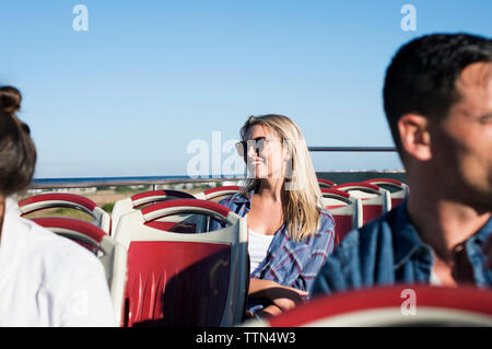 Tourists traveling in double-decker bus against clear blue sky Stock Photo