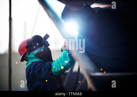 Side view of worker welding container ship at industry Stock Photo