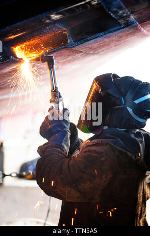 Side view of worker welding ship at industry Stock Photo