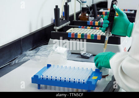 Cropped image of scientist pipetting sample into container in laboratory Stock Photo