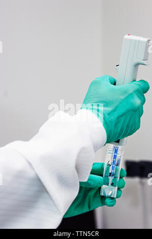 Cropped image of scientist pipetting sample into test tube in laboratory Stock Photo