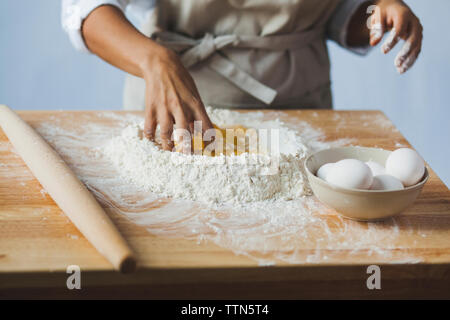 Midsection of woman kneading dough on table while standing in kitchen Stock Photo