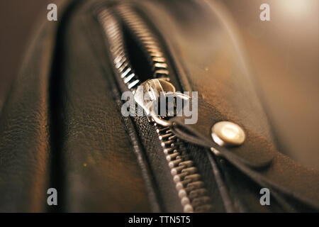 Metal zipper on the pocket on the black leather bag, illuminated by light Stock Photo