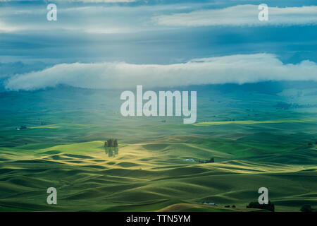 Scenic view of green landscape against cloudy sky Stock Photo