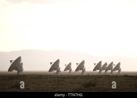 Satellite dishes on field against sky during foggy weather Stock Photo