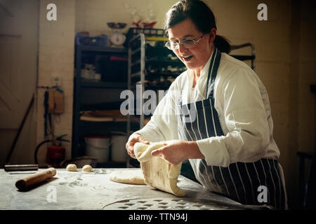 Female baker preparing bread dough in commercial kitchen Stock Photo