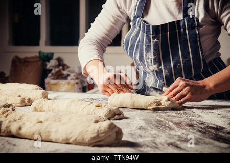Midsection of female baker preparing breadstick dough at table Stock Photo