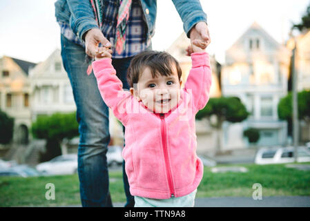 Midsection of mother assisting daughter in walking on street Stock Photo