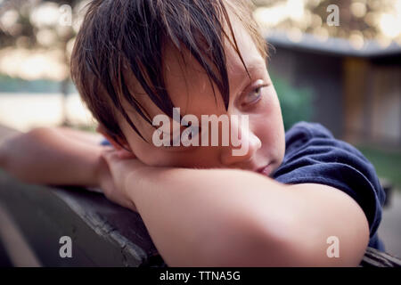 Close-up of thoughtful boy leaning on bench at park Stock Photo
