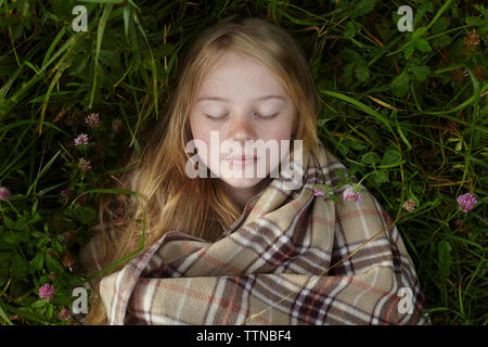 Overhead view of woman with blanket sleeping on field at yard Stock Photo
