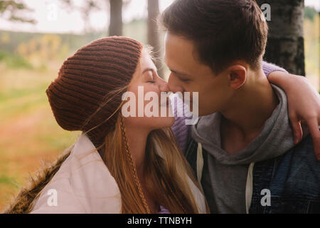 Close-up of romantic young couple kissing while sitting in forest Stock Photo