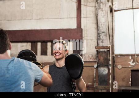 Happy female boxer practicing with friend in gym Stock Photo