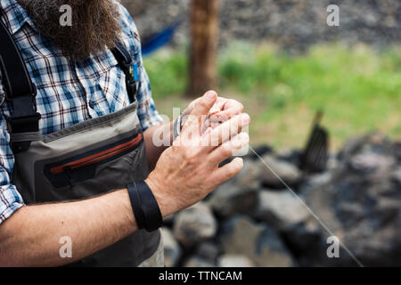 Midsection of mature man holding fishing thread on field Stock Photo