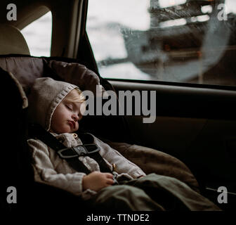 Toddler sleeping in carseat in back of car Stock Photo