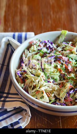 High angle view of coleslaw served in bowl with napkin on wooden table at home Stock Photo