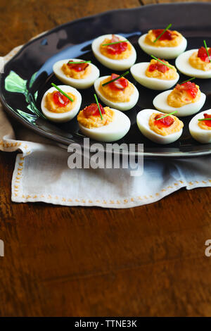 High angle view of deviled eggs served in plate with napkin on wooden table Stock Photo