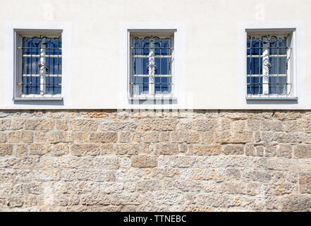 Nice old housewall, bright paint and ancient windows. Painted wall and brick wall combined. Stock Photo