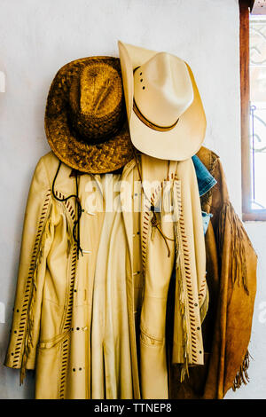 Cowboy hats with coats hanging on wall Stock Photo