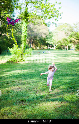 Full length of girl flying kite while running on field Stock Photo