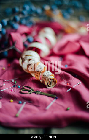 Close-up of scissors, straight pins and tape measure on dress Stock Photo