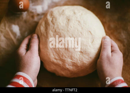 Cropped hands of woman kneading dough on wooden table at home Stock Photo