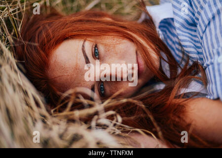 Close-up portrait of teenage girl with red head lying on grassy field Stock Photo