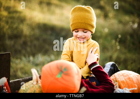 A boy plays with his brother sitting in a cart on the field. Stock Photo