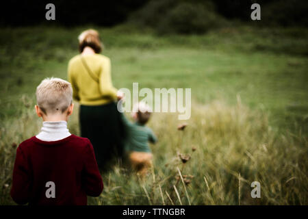 A trio of family walking from behind  in the meadow Stock Photo