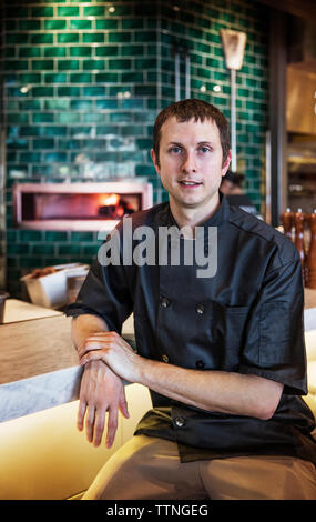 Portrait of confident chef sitting in commercial kitchen Stock Photo