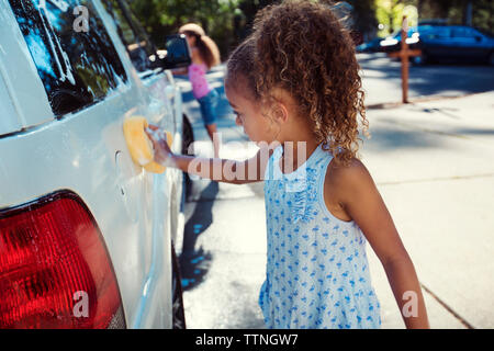 Girls washing car in driveway Stock Photo