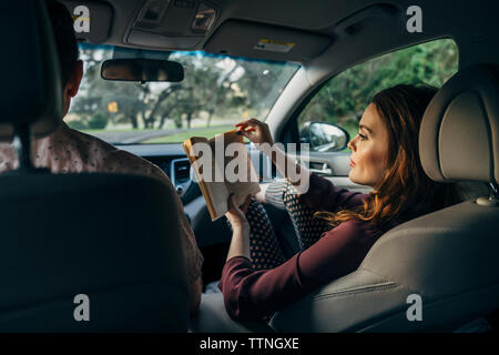 Wife reading book while traveling with husband in car Stock Photo