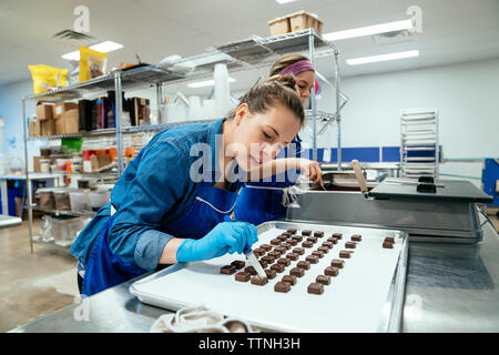 Female coworkers preparing chocolates at factory Stock Photo