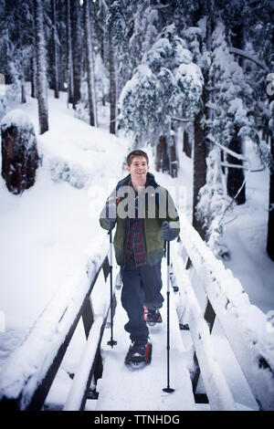 Young hiker on footbridge in winter Stock Photo