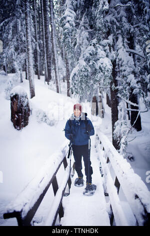 Young hiker on footbridge in winter Stock Photo