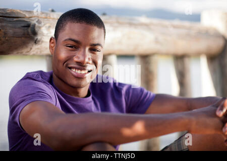 Portrait of happy man sitting by railing Stock Photo