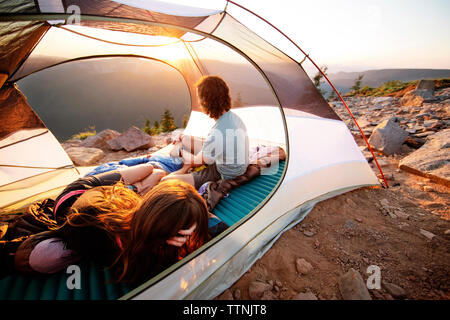Couple relaxing in tent on mountain Stock Photo