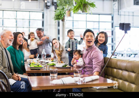 Happy family taking selfie while having dinner in restaurant Stock Photo