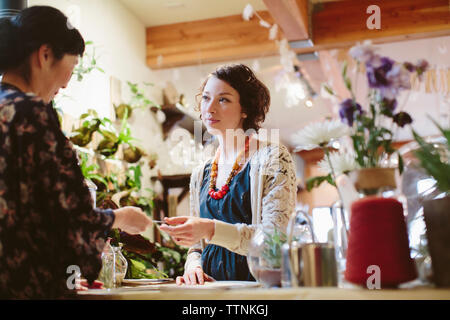 Owner taking credit card from customer at counter in plant shop Stock Photo