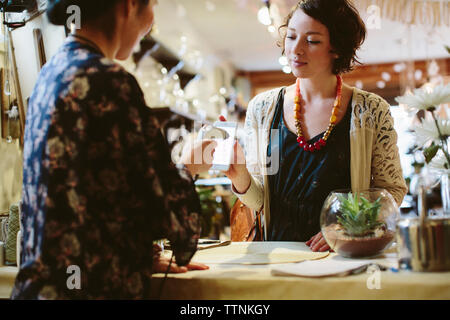 Owner scanning QR code from mobile phone holding by customer in plant shop Stock Photo