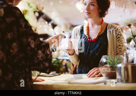 Midsection of owner scanning QR code from mobile phone holding by customer in plant shop Stock Photo