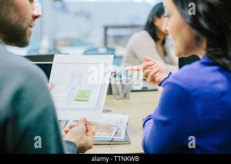 Doctors discussing while examining reports in medical room at hospital Stock Photo