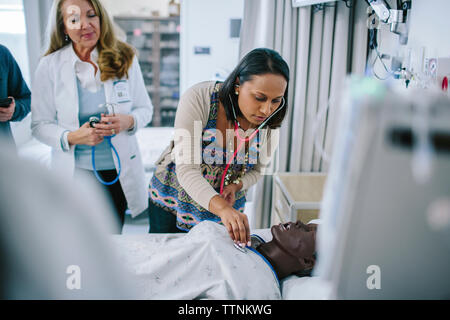 Female doctor training coworkers while examining mannequin in medical school Stock Photo