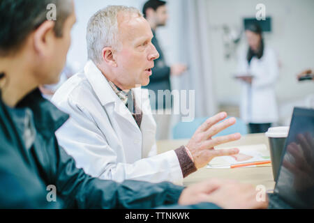 Doctors discussing at table in medical room at hospital Stock Photo