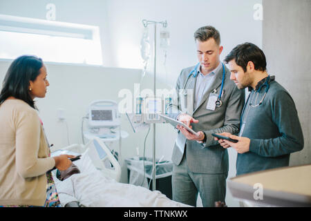 Male doctor training coworkers over tablet computer in medical school Stock Photo