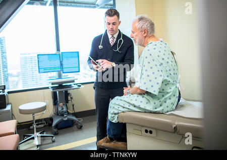 Male doctor explaining to patient over tablet computer in hospital ward Stock Photo