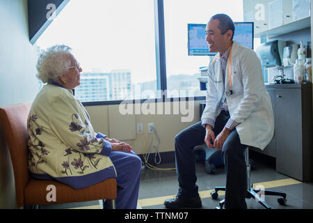 Smiling male doctor talking to patient in hospital ward Stock Photo