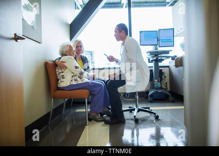 Female patient with daughter talking to male doctor in hospital ward Stock Photo