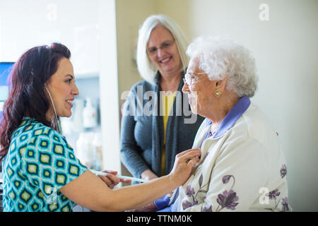 Daughter looking at female doctor examining mother in hospital ward Stock Photo