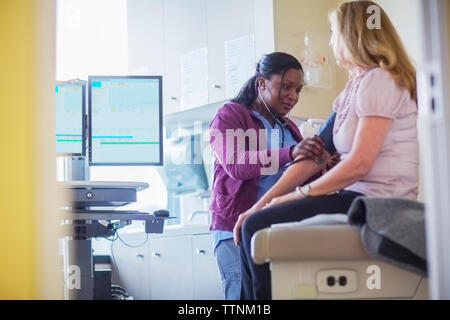 Female doctor examining patient with stethoscope in medical room Stock Photo