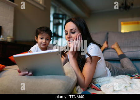 Girl looking at mother using tablet computer at home Stock Photo